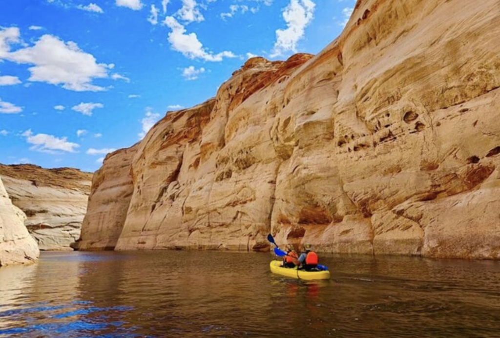 Boat cruising on Lake Powell with red rock formations in the background